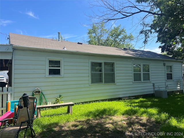 back of property featuring cooling unit and a yard