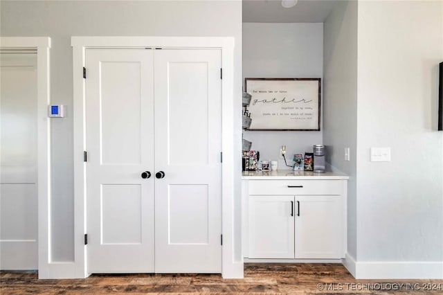 bar with white cabinetry and dark hardwood / wood-style floors