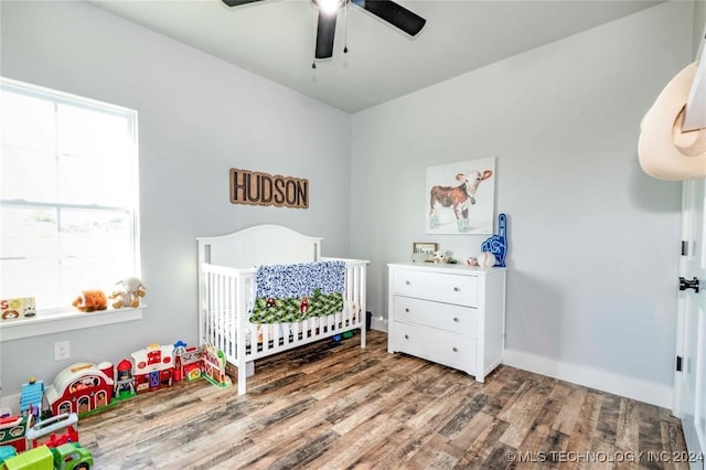 bedroom featuring a crib, hardwood / wood-style floors, and ceiling fan