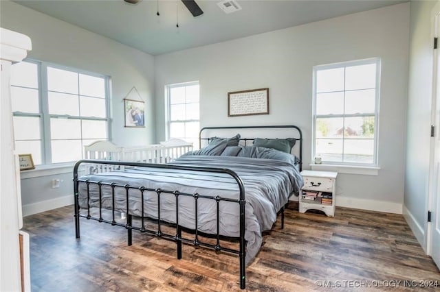 bedroom featuring ceiling fan, dark wood-type flooring, and multiple windows