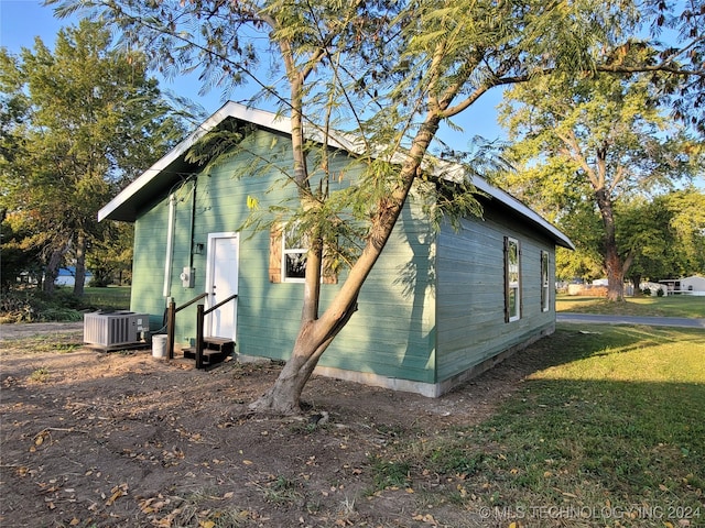 view of side of property with a lawn and central air condition unit