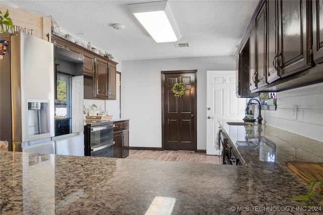 kitchen with dark brown cabinetry, appliances with stainless steel finishes, light wood-type flooring, and sink