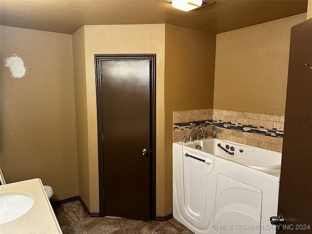 bathroom with vanity, a bathtub, a textured ceiling, and toilet