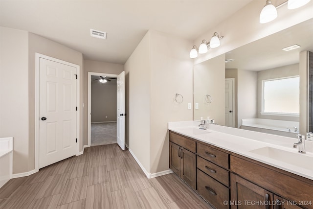 bathroom with ceiling fan, vanity, and a bathing tub