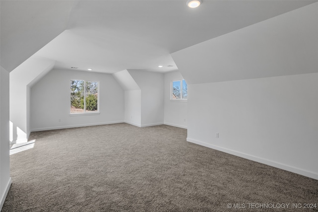 bonus room with lofted ceiling and carpet flooring