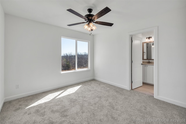 unfurnished bedroom featuring light carpet, ensuite bath, and ceiling fan