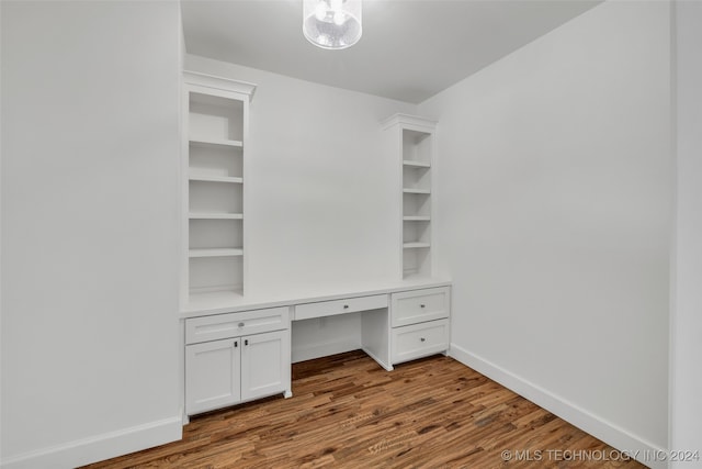 unfurnished office featuring hardwood / wood-style flooring and built in desk