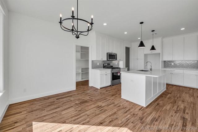 kitchen featuring white cabinets, an island with sink, light hardwood / wood-style flooring, appliances with stainless steel finishes, and decorative backsplash