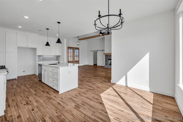 kitchen with light hardwood / wood-style floors, an island with sink, white cabinets, dishwasher, and sink