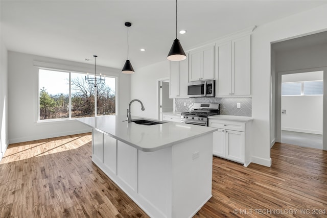 kitchen featuring light wood-type flooring, a kitchen island with sink, sink, white cabinetry, and appliances with stainless steel finishes