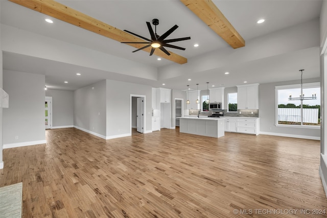 unfurnished living room with light hardwood / wood-style flooring, beam ceiling, and ceiling fan with notable chandelier