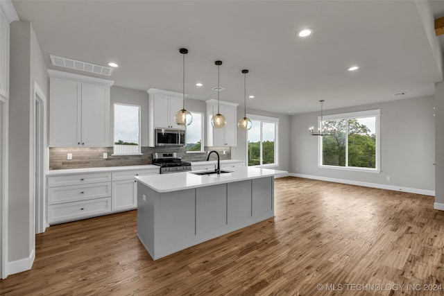 kitchen featuring light hardwood / wood-style floors, tasteful backsplash, white cabinets, stainless steel appliances, and a center island with sink