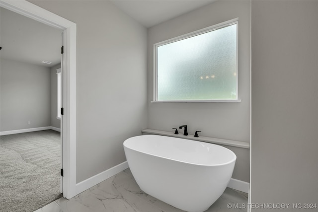 bathroom with a tub to relax in and a healthy amount of sunlight