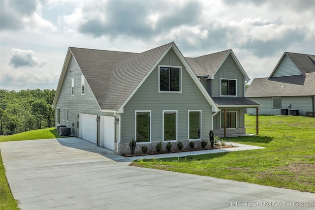 view of front of property with a front lawn, central AC unit, and a garage