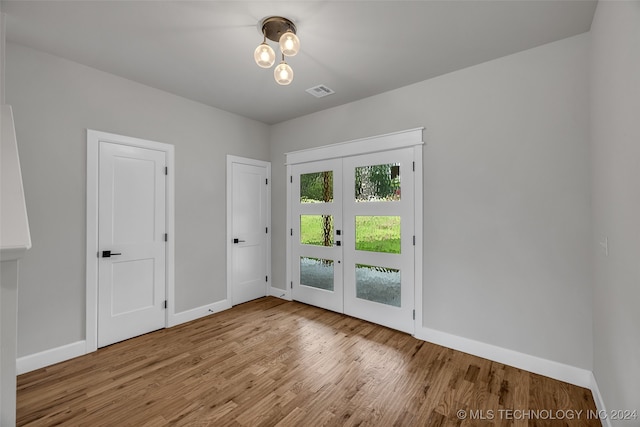 unfurnished room featuring french doors and light hardwood / wood-style flooring