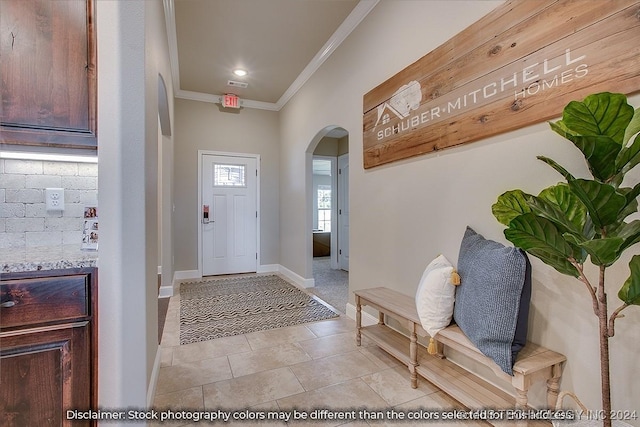 foyer with light tile patterned floors, arched walkways, ornamental molding, visible vents, and baseboards
