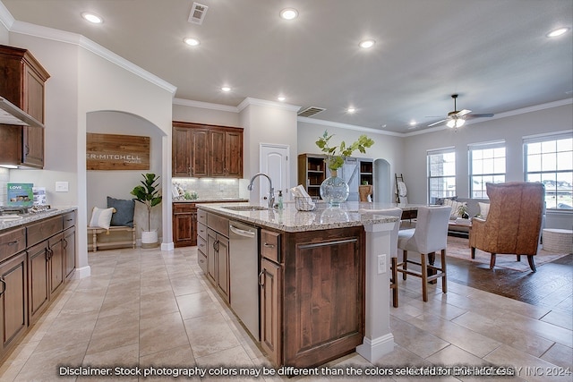 kitchen featuring ceiling fan, sink, stainless steel dishwasher, a kitchen island with sink, and crown molding