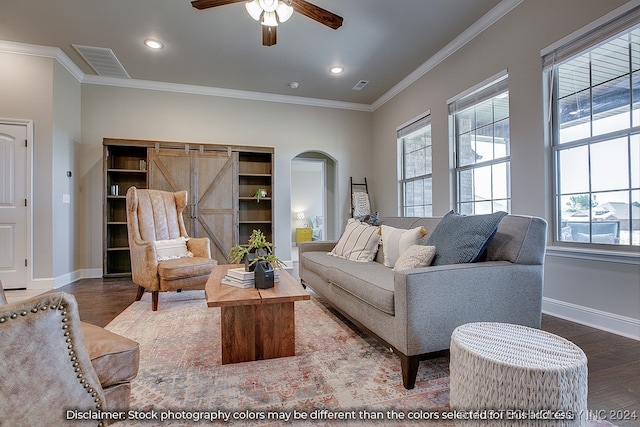 living room featuring ceiling fan, ornamental molding, hardwood / wood-style flooring, and a barn door