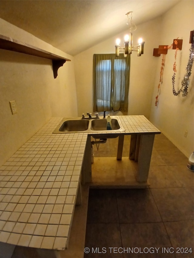 kitchen with lofted ceiling, tile counters, hanging light fixtures, and dark tile patterned flooring