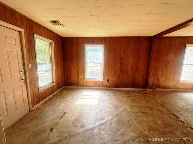 1721 Bighill Ave, Pawhuska, OK 74056 - unfurnished room featuring healthy amount of natural light, wooden walls, tile patterned floors, and baseboards