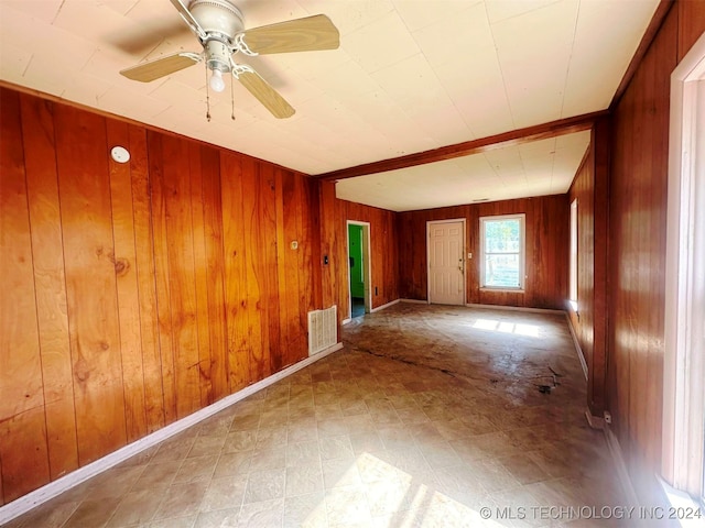 empty room featuring wooden walls and ceiling fan