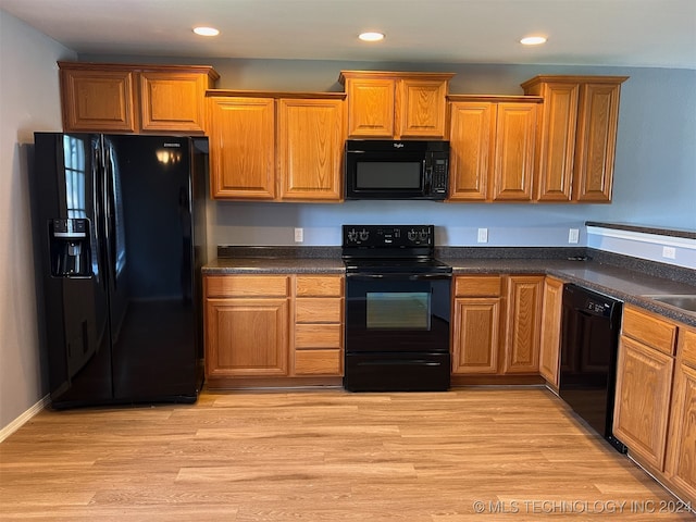 kitchen with black appliances, sink, and light hardwood / wood-style flooring