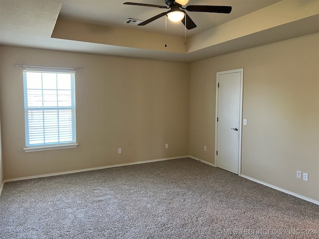 carpeted spare room featuring a raised ceiling and ceiling fan