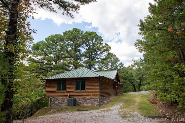 view of property exterior featuring driveway, a standing seam roof, cooling unit, and faux log siding