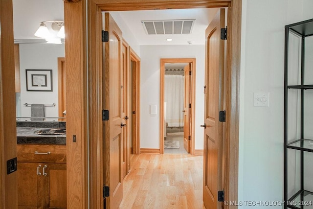 hall with visible vents, light wood-style flooring, and baseboards