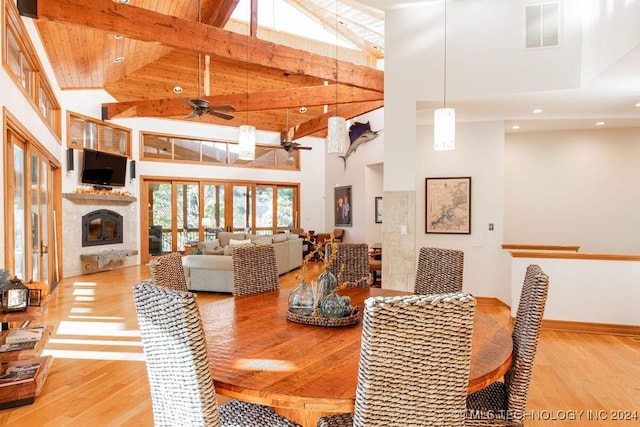 dining space with ceiling fan, high vaulted ceiling, visible vents, light wood-type flooring, and a glass covered fireplace