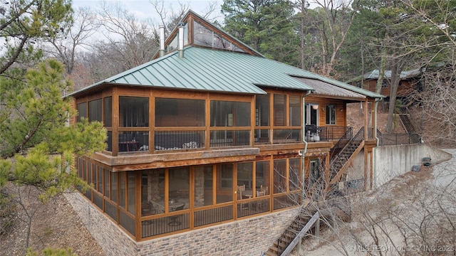 rear view of house with a sunroom, metal roof, stairway, and a standing seam roof