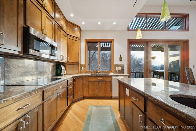 kitchen featuring dark stone counters, stainless steel appliances, brown cabinetry, and backsplash