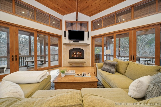 living room featuring high vaulted ceiling, wooden ceiling, a fireplace, wood finished floors, and french doors