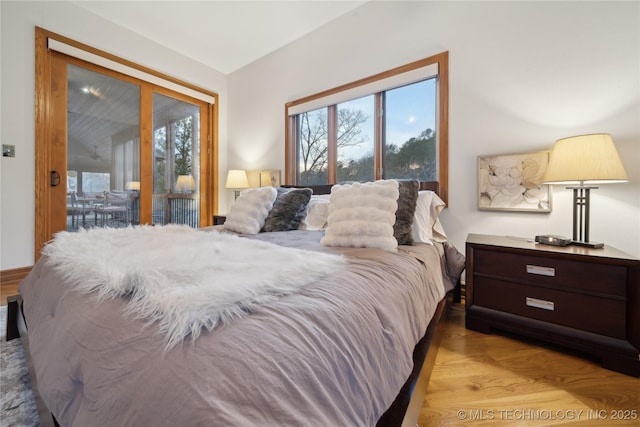 bedroom featuring access to outside, multiple windows, and wood finished floors