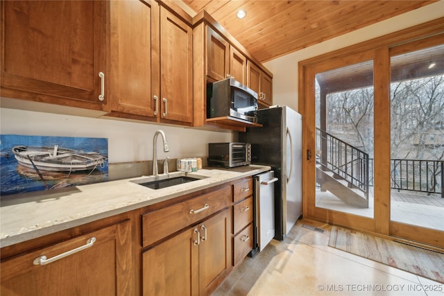 kitchen featuring light stone counters, appliances with stainless steel finishes, brown cabinetry, a sink, and wooden ceiling