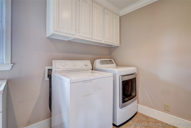 clothes washing area with cabinets, crown molding, washing machine and dryer, and light tile patterned flooring