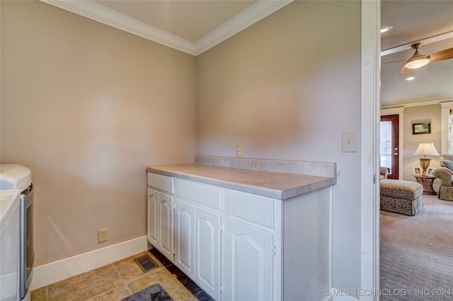 kitchen featuring ornamental molding, light carpet, washing machine and clothes dryer, and white cabinetry