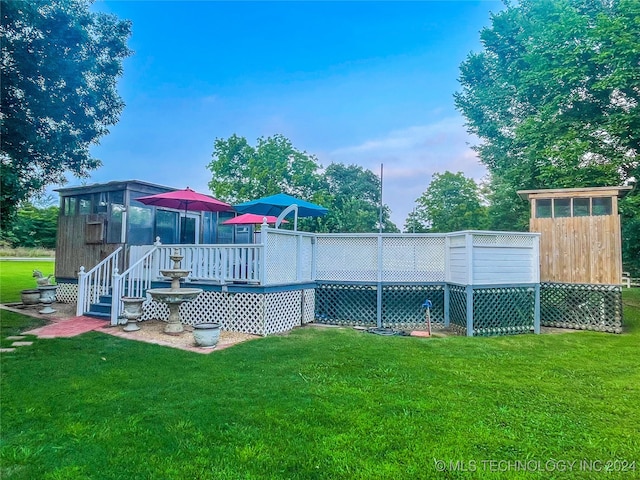 view of pool with a wooden deck and a lawn