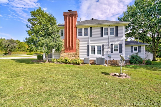 rear view of house with a lawn and central AC