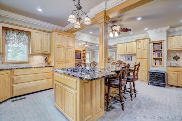 kitchen featuring pendant lighting, a center island, light colored carpet, light stone countertops, and ornate columns