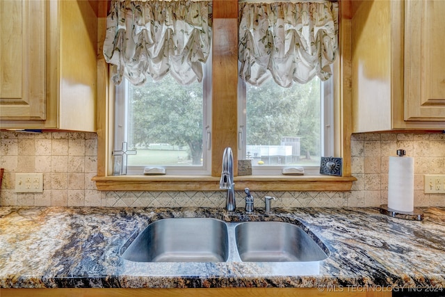 kitchen featuring plenty of natural light, sink, and dark stone counters