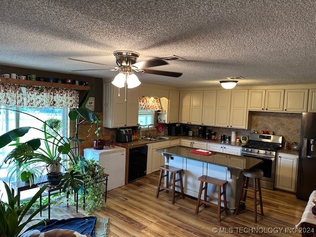 kitchen with sink, a kitchen island, stainless steel appliances, a breakfast bar, and light wood-type flooring