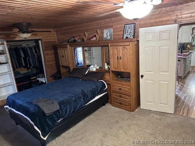 bedroom featuring ceiling fan, wooden walls, light hardwood / wood-style flooring, and a closet