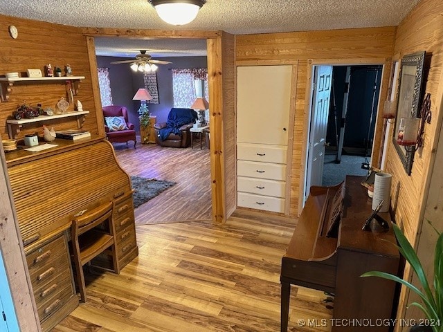 office space with ceiling fan, hardwood / wood-style flooring, wooden walls, and a textured ceiling