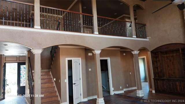 interior space with ornate columns, hardwood / wood-style flooring, crown molding, and a towering ceiling