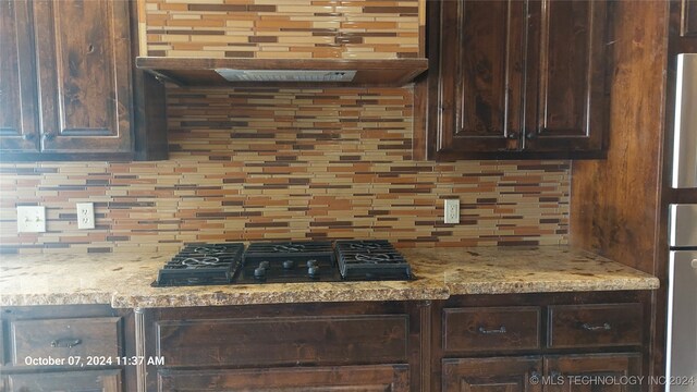 kitchen with light stone counters, decorative backsplash, black gas cooktop, and dark brown cabinetry