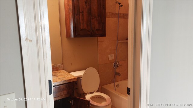 full bathroom featuring tiled shower / bath, vanity, and toilet