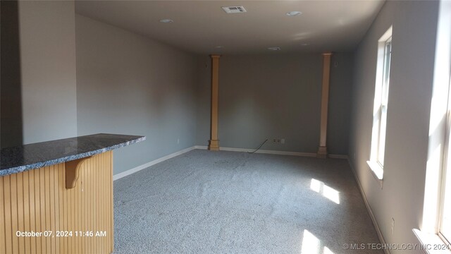 spare room featuring bar area and light carpet