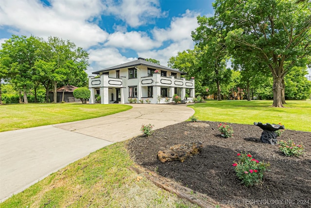 view of front of house featuring a balcony and a front lawn