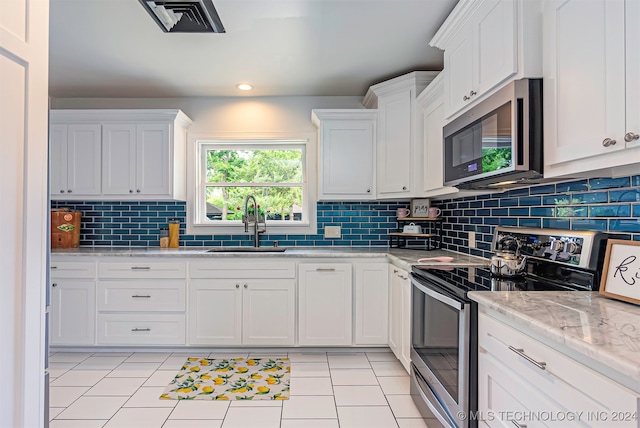 kitchen with light stone countertops, tasteful backsplash, sink, white cabinetry, and appliances with stainless steel finishes